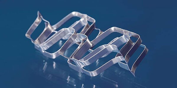 Ein Füllkörper aus Metall liegt auf einem blauen Hintergrund.